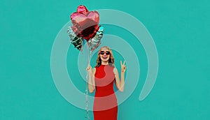 Happy smiling woman with bunch of red heart shaped balloons on blue background