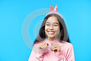 Happy smiling woman with bunny ears posing over blue background