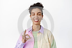 Happy smiling woman close eyes, showing okay OK sign, zero gesture, no proble, praise awesome good thing, standing in