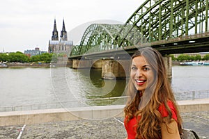 Happy smiling woman in Cologne with Cathedral and Bridge on River Rhine on the background, Cologne, Germany. Traveling in Europe.
