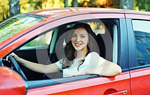 Happy smiling woman driver behind wheel red car