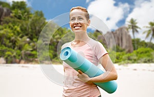 Happy smiling woman with exercise mat over beach