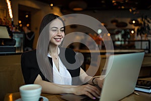 Happy smiling woman in fashionable clothes having online training course on laptop computer