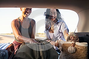 Happy smiling woman freinds put bag and luggage into car trunk
