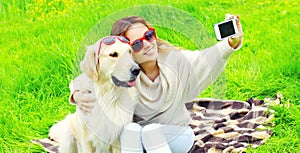 Happy smiling woman with Golden Retriever dog taking selfie picture by phone in summer