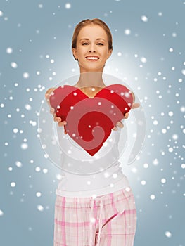 Happy and smiling woman with heart-shaped pillow