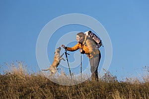 Happy smiling woman hiking in mountains with dog