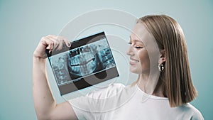 Happy smiling woman hold dental x ray of teeth and showing close up to the camera. Smile healthy teeth concept, dental