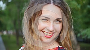 A happy smiling woman laughs fervently on a city street. Curly attractive caucasian woman closeup portrait summer time