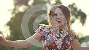 A happy smiling woman laughs fervently on a city street. Curly attractive caucasian woman closeup portrait summer time