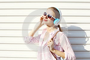 Happy smiling woman listens to music in headphones over white