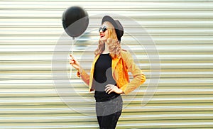 happy smiling woman looking at black helium air balloon in round hat