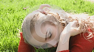 Happy smiling woman lying on green grass enjoying life, young female having fun outdoors in spring park.