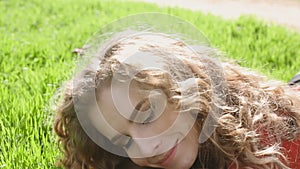 Happy smiling woman lying on green grass enjoying life, young female having fun outdoors in spring park.