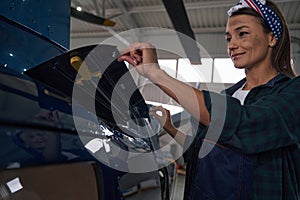 Beautiful Caucasian female engineer in uniform inspecting details of helicopter