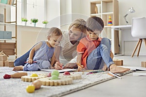 Happy smiling woman mother and children drawing together with pencils at home