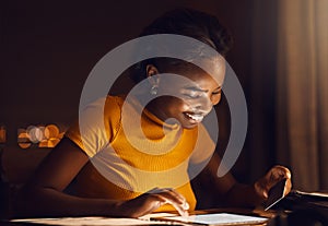 Happy, smiling woman paying bills, loans and shopping online on her tablet in the late evening at home. Single African