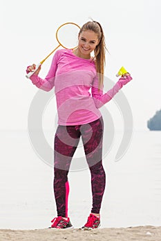 Happy smiling woman playing badminton at beach, active lifestyle