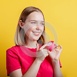 Happy Smiling Woman Portrait applying moisturizing cream hand cream look side on copy space. Teenager girl using