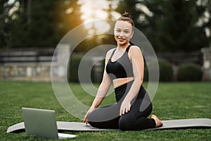 Happy smiling woman practicing yoga meditating online in garden outdoors during quarantine. Meditation and relaxation at home