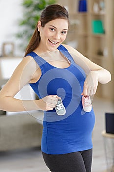 happy smiling woman in pregnant with baby shoes