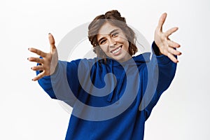 Happy smiling woman reaching hands, girl stretching arms to receive gift, hug or welcome you, standing in blue hoodie
