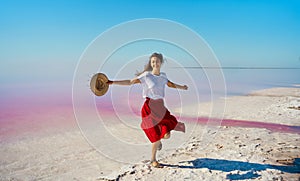 Happy smiling woman in red skirt dancing, dynamic moving at salt flats of pink lake