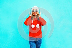 Happy smiling woman in red sweater, listens to music in wireless headphones