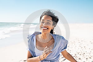 Happy smiling woman running on beach in a beautiful summer day