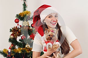 Happy smiling woman in Santa hat with toy terrier near Christmas