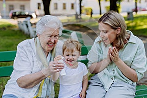 Happy smiling woman with senior grandmother and little daughter blowing soap bubbles at park, family, generation and