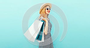 Happy smiling woman with shopping bags wearing a summer straw round hat, black white striped dress on a blue background