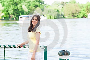 Happy smiling woman sitting in the park by lake