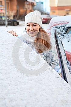 Happy smiling woman standing near of snow covered car