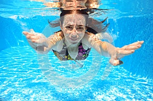 Happy smiling woman swims underwater in pool