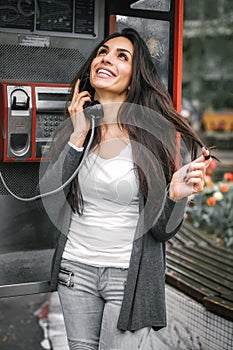 Happy and smiling woman talking in the retro phone booth