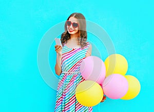 happy smiling woman using smartphone holding an air colorful balloons