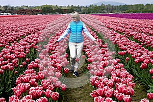 Happy smiling woman walking through colourful tulip fields.