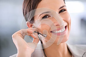 Happy and smiling woman wearing a headset working in a call centre portrait. Young, beautiful and confident professional