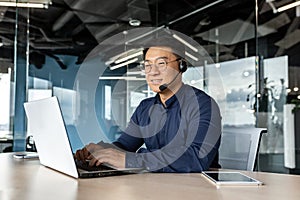 Happy and smiling worker with headset for video call, Asian tech support man talking to online service users