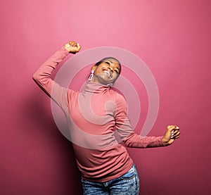 Happy smiling young afro woman dancing isolated on pink color background