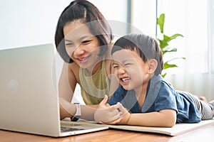 Happy Smiling Young Asian mother and little son looking at Laptop