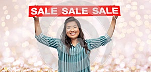 Happy smiling young asian woman with sale banner