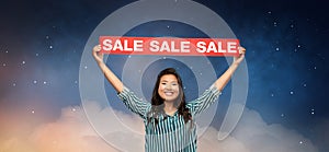 Happy smiling young asian woman with sale banner