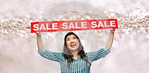 Happy smiling young asian woman with sale banner