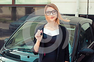 Happy, smiling, young attractive woman, buyer near her new car showing keys