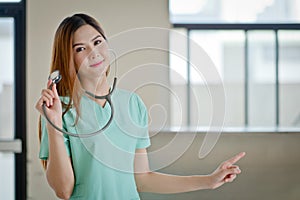 Happy smiling young beautiful female doctor showing blank area f