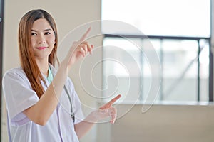 Happy smiling young beautiful female doctor showing blank area f