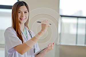 Happy smiling young beautiful female doctor showing blank area f