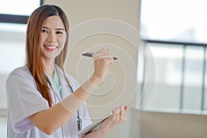 Happy smiling young beautiful female doctor showing blank area f